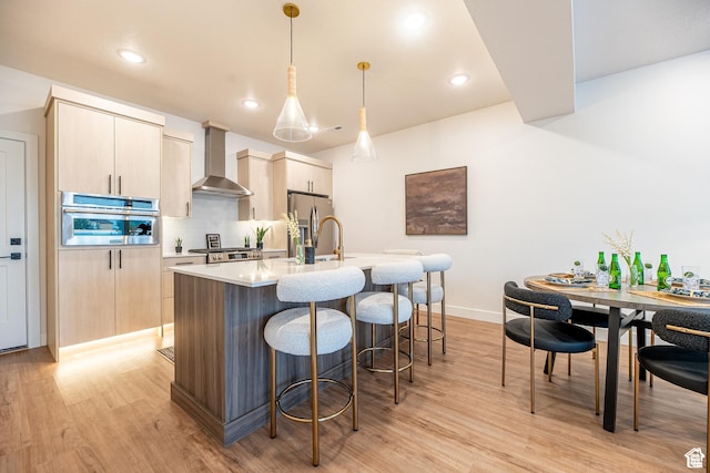 4337 W 5430 S Unit D, Roy, UT 84067 - kitchen featuring wall chimney range hood, stainless steel appliances, light wood-style flooring, an island with sink, and a sink