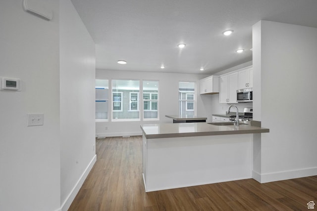 1776 W 160 S Unit 50, Pleasant Grove, UT 84062 - kitchen with stainless steel appliances, white cabinetry, wood finished floors, a peninsula, and recessed lighting