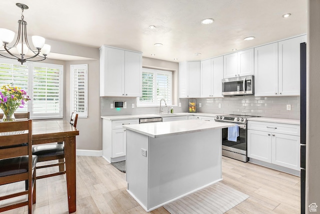 137 Stern Ct, Stansbury Park, UT 84074 - kitchen featuring stainless steel appliances, a chandelier, light wood-style flooring, light countertops, and white cabinetry