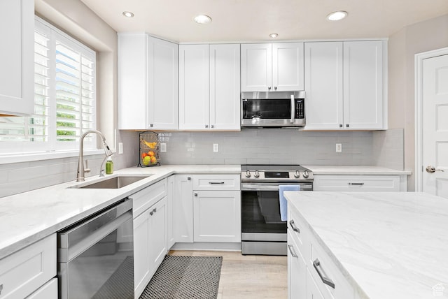 137 Stern Ct, Stansbury Park, UT 84074 - kitchen with appliances with stainless steel finishes, a sink, light stone counters, white cabinetry, and tasteful backsplash