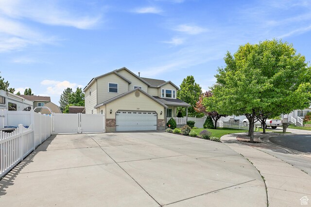 137 Stern Ct, Stansbury Park, UT 84074 - view of front of house featuring concrete driveway, brick siding, a garage, and a gate