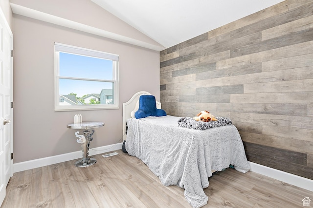 137 Stern Ct, Stansbury Park, UT 84074 - bedroom featuring vaulted ceiling, wood walls, light wood-style flooring, baseboards, and an accent wall