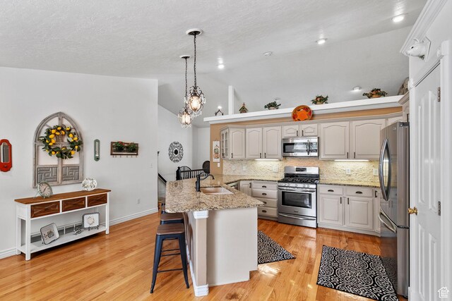 896 E 380 N, Heber City, UT 84032 - kitchen featuring appliances with stainless steel finishes, a peninsula, a kitchen bar, backsplash, and light wood-style flooring