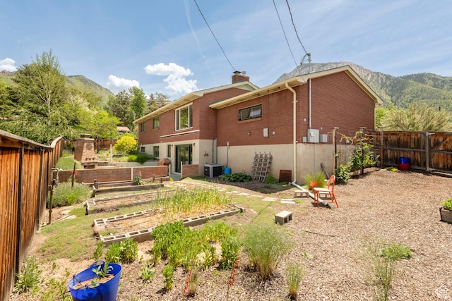 3555 E Hermes Dr S, Salt Lake City, UT 84124 - rear view of property featuring a vegetable garden, brick siding, a mountain view, central AC, and a chimney