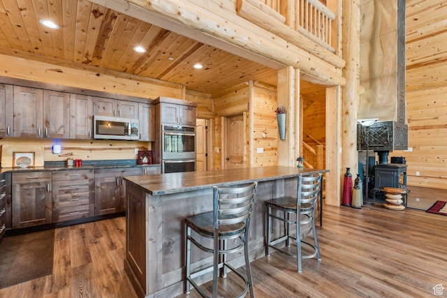 4708 Red Fir Way, Oakley, UT 84055 - kitchen with appliances with stainless steel finishes, a wood stove, recessed lighting, a breakfast bar, and dark wood finished floors