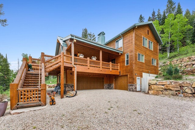 4708 Red Fir Way, Oakley, UT 84055 - rear view of property with stairway, stone siding, an attached garage, gravel driveway, and a deck