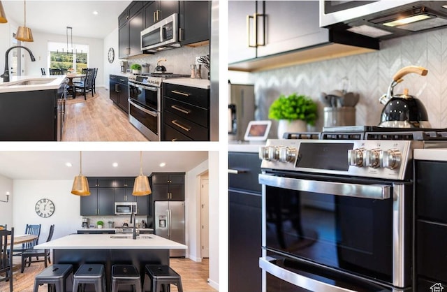 12852 N Belaview Way, Hideout, UT 84036 - kitchen featuring appliances with stainless steel finishes, a sink, a center island with sink, light wood-style floors, and dark cabinets