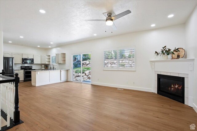 494 E 3525 N, North Ogden, UT 84414 - unfurnished living room with light wood-style floors, a fireplace, recessed lighting, ceiling fan, and baseboards