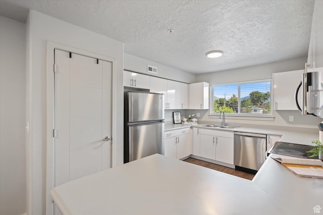 67 W 600 S Unit B204, Springville, UT 84663 - kitchen featuring stainless steel appliances, wood finished floors, a sink, white cabinets, and a peninsula