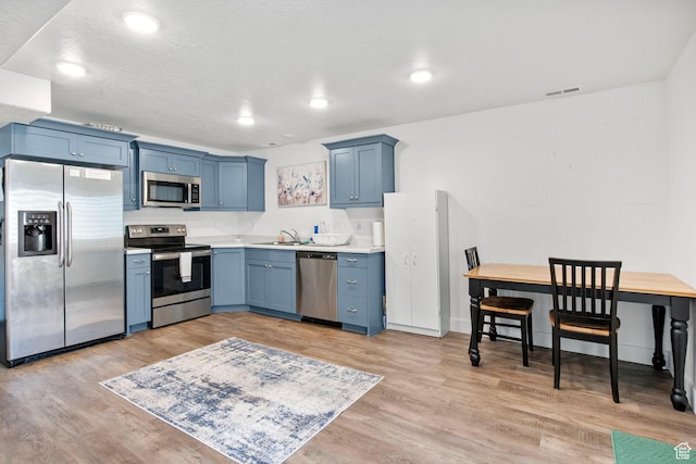 432 W 1470 N, Tooele, UT 84074 - kitchen featuring appliances with stainless steel finishes, light countertops, light wood-style flooring, blue cabinetry, and recessed lighting
