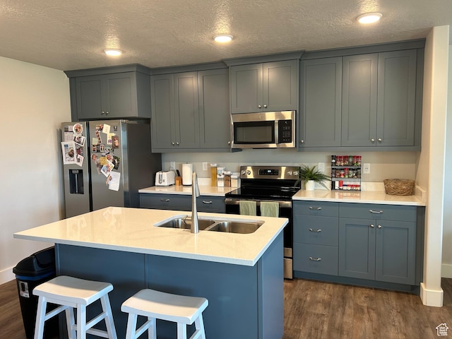 432 W 1470 N, Tooele, UT 84074 - kitchen featuring appliances with stainless steel finishes, a sink, dark wood-style floors, a breakfast bar area, and a textured ceiling