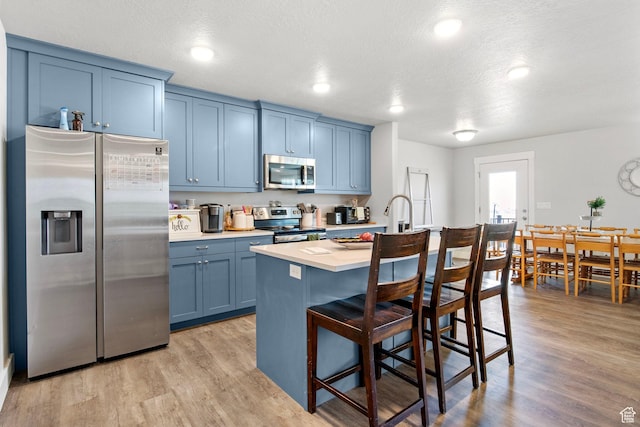 432 W 1470 N, Tooele, UT 84074 - kitchen featuring appliances with stainless steel finishes, blue cabinets, light countertops, a kitchen bar, and a center island with sink
