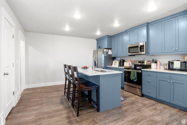 432 W 1470 N, Tooele, UT 84074 - kitchen featuring appliances with stainless steel finishes, blue cabinetry, a breakfast bar, a center island with sink, and recessed lighting
