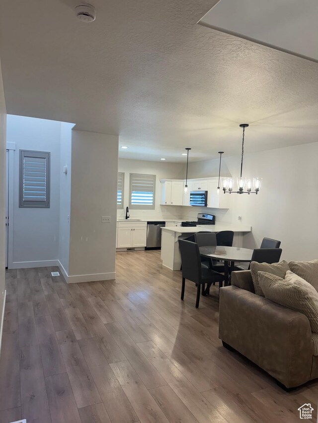 4569 W Ruple Ridge Ln S, Herriman, UT 84096 - living room with a textured ceiling, wood finished floors, a chandelier, and baseboards