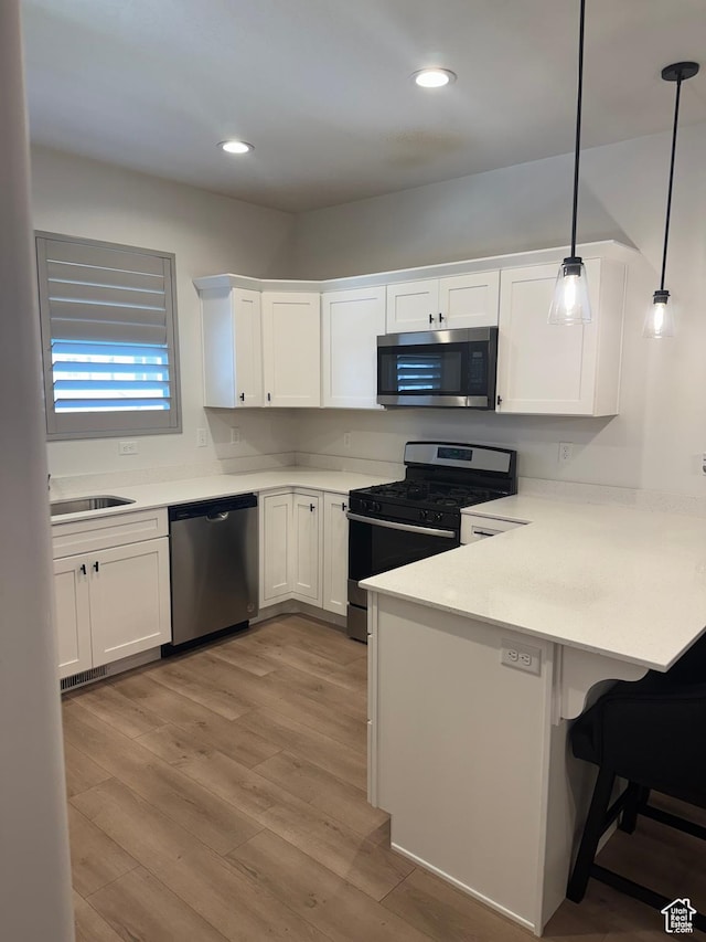4569 W Ruple Ridge Ln S, Herriman, UT 84096 - kitchen featuring appliances with stainless steel finishes, a peninsula, white cabinetry, a kitchen breakfast bar, and recessed lighting