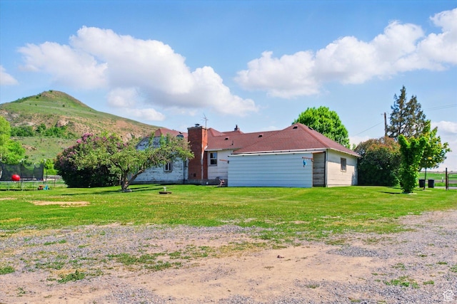 1411 E 13000 N, Cove, UT 84320 - back of property featuring a yard, a trampoline, a mountain view, and a chimney