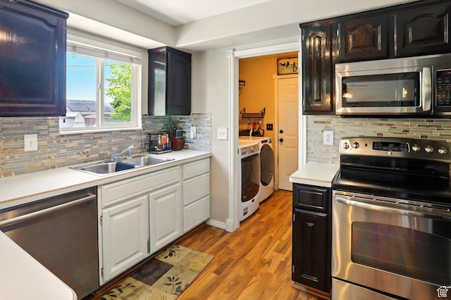 2223 S Allison Way, Syracuse, UT 84075 - kitchen with stainless steel appliances, washing machine and dryer, a sink, light wood-style flooring, and light countertops