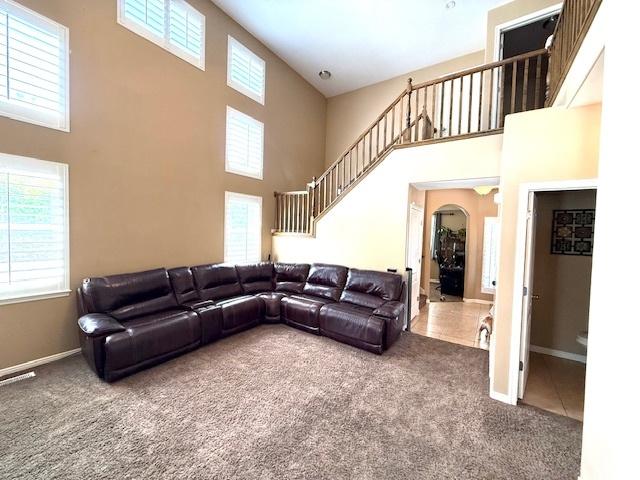 1093 S 1960 E, Spanish Fork, UT 84660 - carpeted living area with a high ceiling, healthy amount of natural light, stairway, and arched walkways