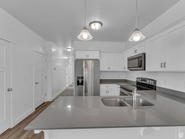 14569 S Bloom Dr W Unit L204, Herriman, UT 84096 - kitchen with stainless steel appliances, a sink, white cabinets, dark countertops, and a peninsula