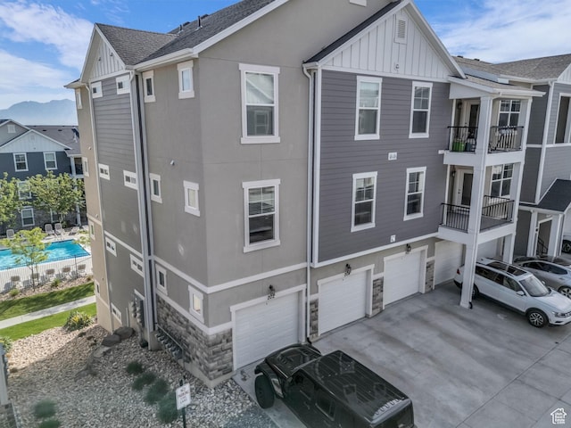 14569 S Bloom Dr W Unit L204, Herriman, UT 84096 - rear view of house featuring board and batten siding, a garage, stone siding, concrete driveway, and stucco siding