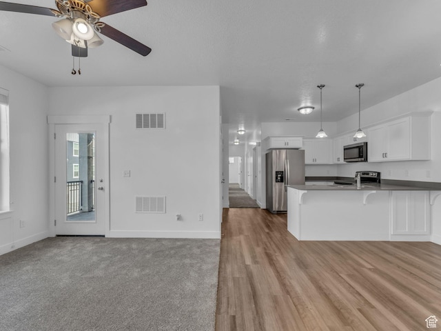 14569 S Bloom Dr W Unit L204, Herriman, UT 84096 - kitchen with appliances with stainless steel finishes, a ceiling fan, a peninsula, a breakfast bar area, and white cabinetry
