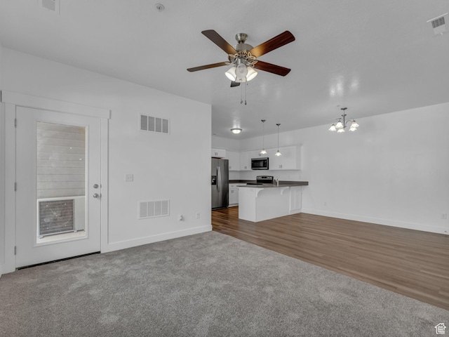 14569 S Bloom Dr W Unit L204, Herriman, UT 84096 - unfurnished living room with baseboards, a ceiling fan, dark carpet, and a chandelier