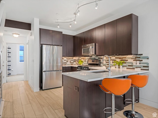 7701 S Navarro View Ct, Midvale, UT 84047 - kitchen featuring appliances with stainless steel finishes, a sink, a peninsula, dark brown cabinets, and light countertops