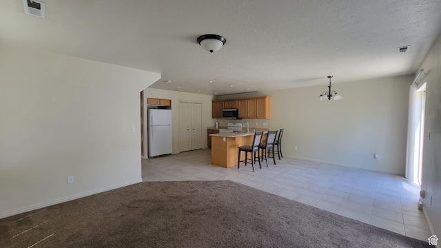 581 S 910 W Unit 86, Pleasant Grove, UT 84062 - kitchen featuring freestanding refrigerator, stainless steel microwave, a breakfast bar area, a chandelier, and a peninsula