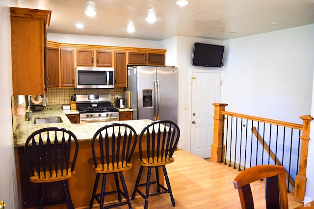 264 W 550 N, Santaquin, UT 84655 - kitchen featuring stainless steel appliances, a peninsula, decorative backsplash, light stone counters, and light wood-style flooring