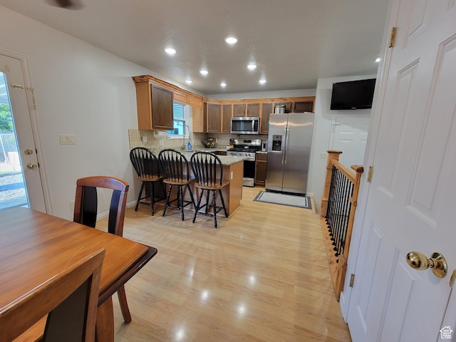 264 W 550 N, Santaquin, UT 84655 - kitchen with appliances with stainless steel finishes, a peninsula, tasteful backsplash, light wood-type flooring, and a breakfast bar area