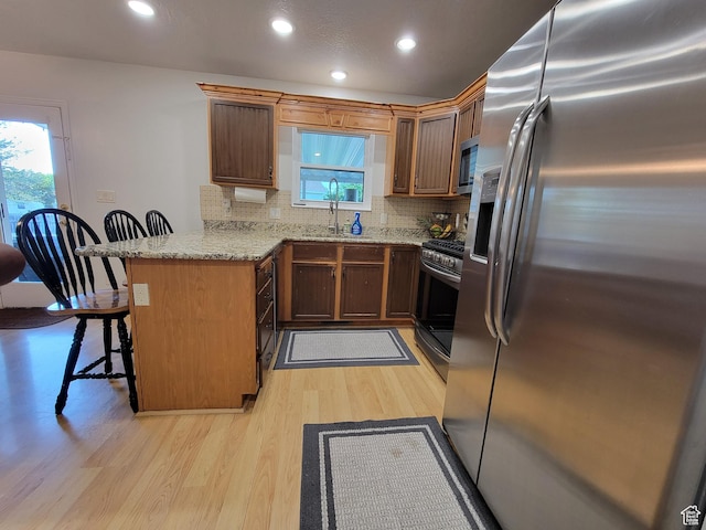 264 W 550 N, Santaquin, UT 84655 - kitchen with appliances with stainless steel finishes, a peninsula, light wood-style flooring, a breakfast bar, and decorative backsplash