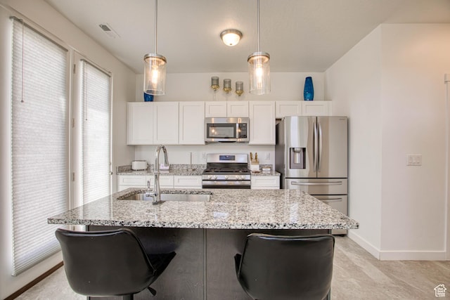 7776 S Iron Core Ln, West Jordan, UT 84081 - kitchen featuring stainless steel appliances, a sink, white cabinets, a center island with sink, and baseboards