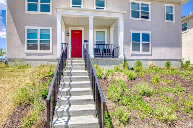 7776 S Iron Core Ln, West Jordan, UT 84081 - doorway to property with stucco siding and a porch