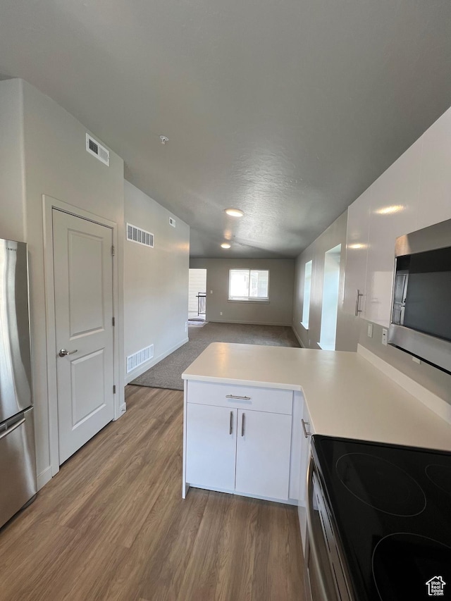 1140 W 950 N Unit C401, Orem, UT 84057 - kitchen featuring stainless steel appliances, a peninsula, light countertops, light wood-style flooring, and vaulted ceiling