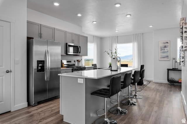 1897 E Thunder Ln Unit 498, Eagle Mountain, UT 84005 - kitchen with stainless steel appliances, an island with sink, a kitchen bar, wood finished floors, and recessed lighting