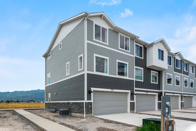 1897 E Thunder Ln Unit 498, Eagle Mountain, UT 84005 - view of front facade featuring an attached garage, stone siding, central AC, driveway, and a mountain view