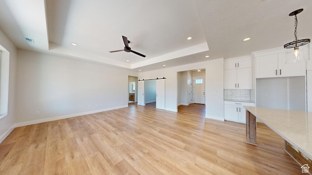 1151 S 4475 W, Cedar City, UT 84720 - unfurnished living room featuring a raised ceiling, a barn door, recessed lighting, ceiling fan, and light wood finished floors