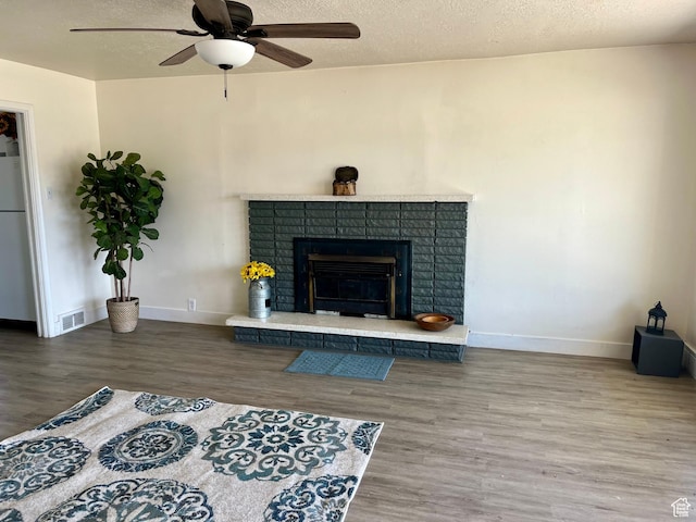 123 S State St, Salina, UT 84654 - living area with wood finished floors, a ceiling fan, a textured ceiling, baseboards, and a fireplace