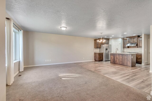1909 E 280 S, Spanish Fork, UT 84660 - unfurnished living room featuring baseboards, a chandelier, a textured ceiling, light carpet, and a sink
