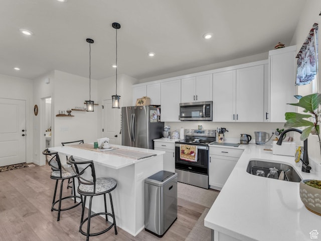 4423 E Longleaf Ln, Eagle Mountain, UT 84005 - kitchen with appliances with stainless steel finishes, a sink, a center island, a kitchen breakfast bar, and light wood-style flooring