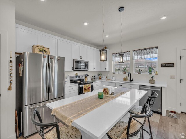 4423 E Longleaf Ln, Eagle Mountain, UT 84005 - kitchen with stainless steel appliances, a sink, a kitchen breakfast bar, light wood-type flooring, and light countertops