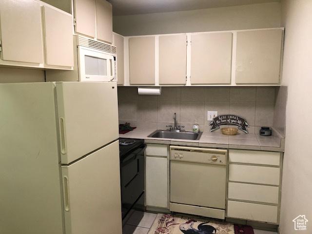 350 E 700 S Unit K102, Salt Lake City, UT 84111 - kitchen with white appliances, a sink, backsplash, tile countertops, and white cabinets