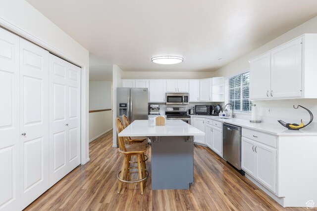 1199 E Pheasant View Dr, Layton, UT 84041 - kitchen with appliances with stainless steel finishes, a kitchen bar, white cabinets, and wood finished floors