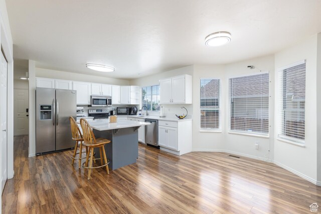 1199 E Pheasant View Dr, Layton, UT 84041 - kitchen with stainless steel appliances, white cabinets, a kitchen bar, light countertops, and a kitchen island