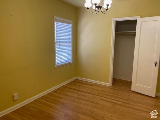 2646 S 1700 E, Salt Lake City, UT 84106 - unfurnished bedroom with a chandelier, baseboards, wood finished floors, and a closet