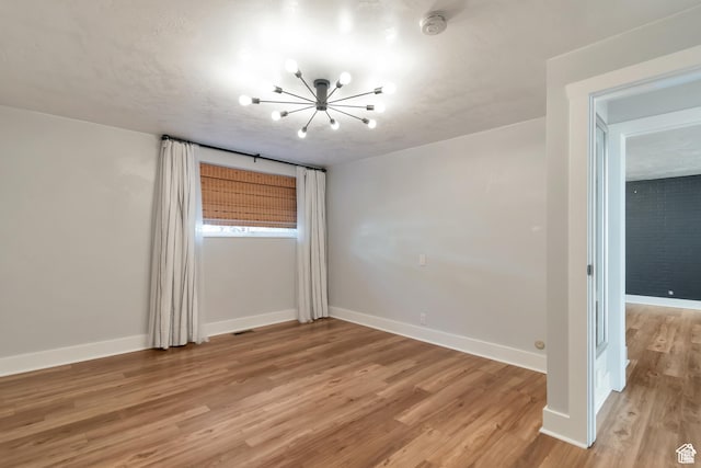 265 N Vine St W Unit 1, Salt Lake City, UT 84103 - empty room featuring a chandelier, light wood-type flooring, baseboards, and a smoke detector