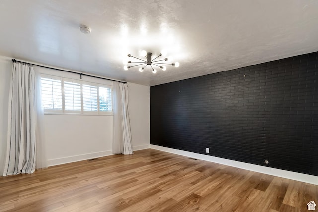 265 N Vine St W Unit 1, Salt Lake City, UT 84103 - spare room featuring a chandelier, brick wall, light wood finished floors, baseboards, and a smoke detector
