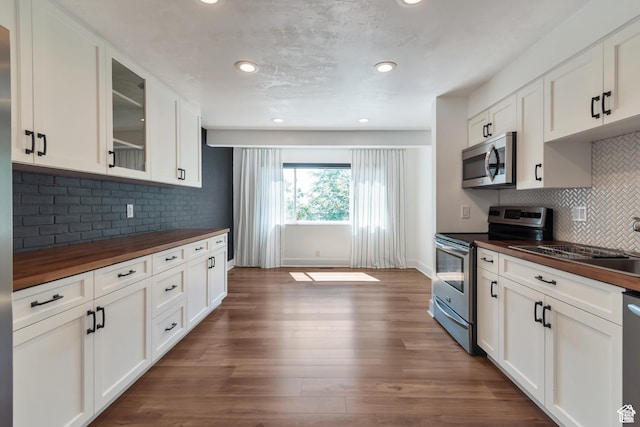 265 N Vine St W Unit 1, Salt Lake City, UT 84103 - kitchen with butcher block countertops, appliances with stainless steel finishes, glass insert cabinets, backsplash, and dark wood-type flooring