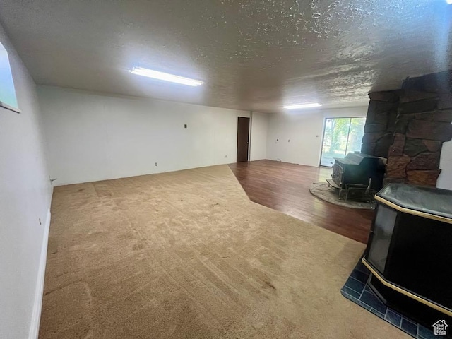 160 E 300 S, Gunnison, UT 84634 - carpeted living area featuring a wood stove, a textured ceiling, and wood finished floors
