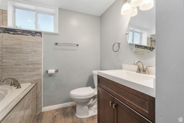 3909 S Rosemary St, West Valley City, UT 84120 - bathroom featuring toilet, tiled bath, wood finished floors, vanity, and baseboards